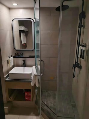 A modern bathroom with a glass-enclosed shower, a white sink, and a mirror above it.