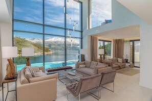 A spacious living area with a large window overlooking a mountainous landscape and a body of water. - Villa Opus (Žrnovo)