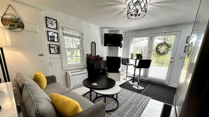 Uma sala de estar moderna com um sofá cinzento, almofadas amarelas, uma mesa de centro redonda e um móvel para TV preto.