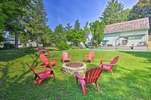 Ein Garten mit Feuerstelle, roten Adirondack-Stühlen und einem Poolbereich.