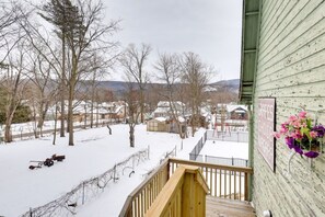 Une terrasse en bois offrant une vue sur un paysage enneigé et des maisons.