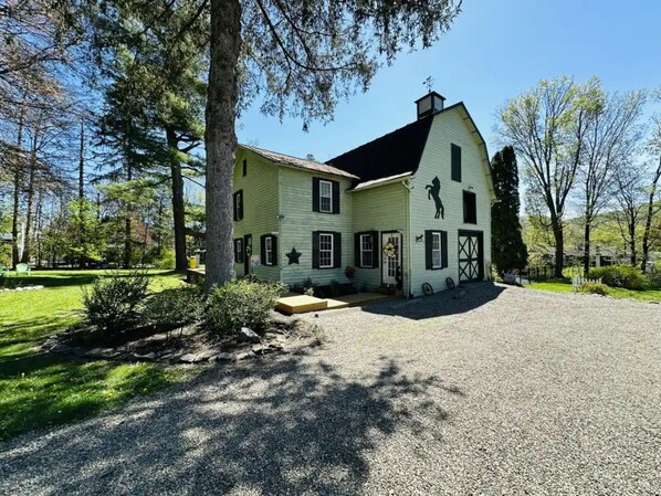A two-story house with a large front porch, a garage, and a driveway leading to the entrance.