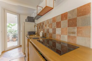 Et moderne køkken med skakmønstret bagvæg, indbygget ovn og en skydedør til en balkon med plantekasser.