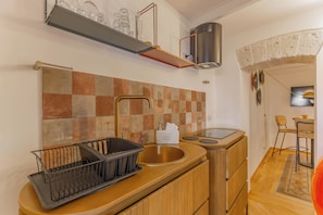 Una cocina compacta con un lavamanos, un escurreplatos, una encimera con dispensador de jabón para platos y una estufa.