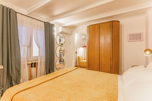 Ett hotellrum med en säng, gardiner, en spegel, en garderob och en lampa.