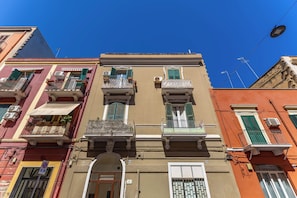 Un edificio de varios pisos con balcones, una puerta con arco y un cielo azul despejado.