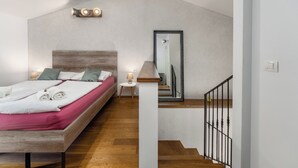 Ein Schlafzimmer mit einem hölzernen Bett, einem Nachttisch, einer Lampe, einem Spiegel und einer Treppe.