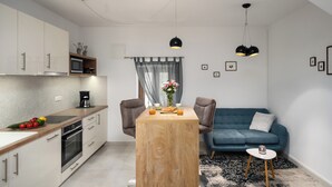 Eine moderne Küche mit Esstisch, Stühlen und einem blauen Sofa.