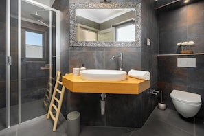 Un baño moderno con cabina de ducha de vidrio, tocador de madera con lavamanos y un inodoro.
