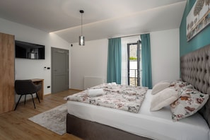 Un dormitorio con cama, escritorio, silla, lámpara colgante y ventana con cortinas.