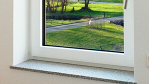 Ein Fenster mit Blick auf eine grüne Landschaft und Bäume.