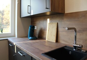 A kitchen with a black sink, wooden countertop, and a coffee maker. - Spacious apartment 8 with use of sauna (Herbolzheim)