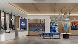 Eine moderne Hotelhalle mit einer Rezeption, einer Sitzecke und einem dekorativen Chandelier.