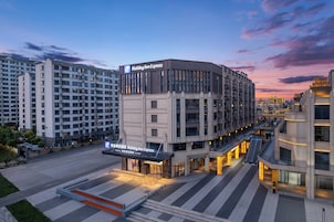 Un hotel Holiday Inn Express de diseño moderno, situado en un entorno urbano con edificios altos aledaños.