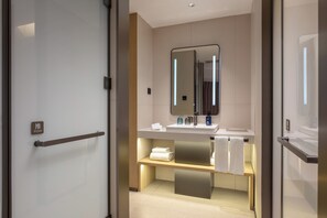 A modern bathroom with a glass door, a mirror, a sink, and a towel rack. - Holiday Inn Express Tangshan Harbor by IHG (Tangshan)