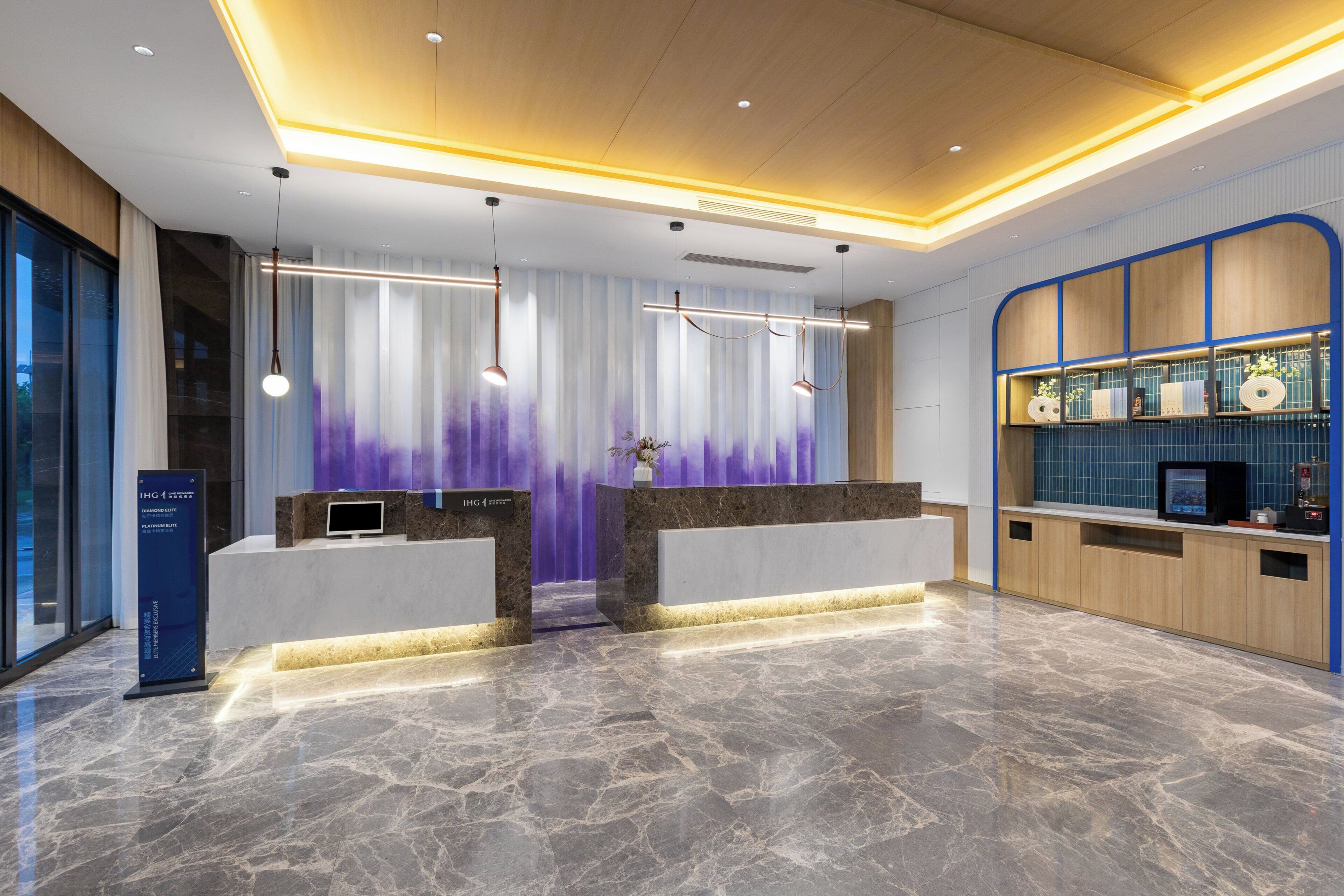 A modern reception area with marble flooring, a reception desk, and a blue-framed display case.