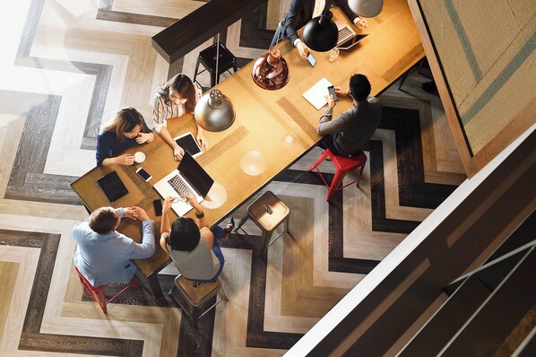 A modern office space with a large wooden table, multiple chairs, and a variety of electronic devices. - Holiday Inn Warner Robins South At Rigbys by IHG (Warner Robins)