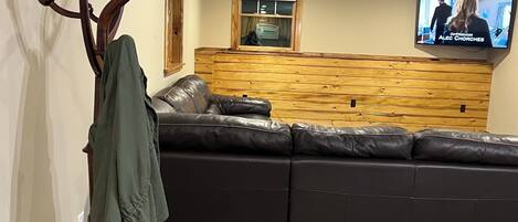 Una sala de estar moderna con un sofá modular, un perchero y un televisor montado en la pared.