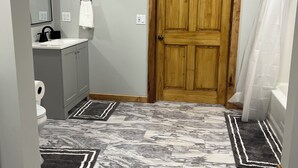 Een badkamer met een houten deur, een spiegel, een wastafel en een toilet.