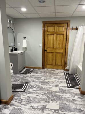 Un baño con puerta de madera, un espejo, un lavamanos y un inodoro.