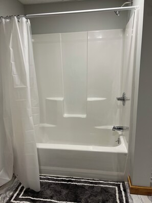 Un baño con bañera, cortina de ducha y alfombra blanco y negro.