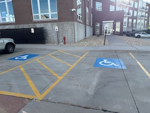 A parking lot with designated handicapped parking spaces and a building entrance. - The Dugout - Baseball Oasis Duplex Condo (Dyersville)