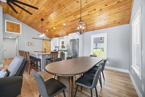 Una cucina moderna con soffitto in legno, una zona pranzo con tavolo rotondo e vista sull'esterno.