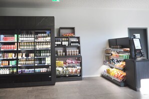 A grocery store interior with refrigerated sections, shelves stocked with beverages and snacks, and a self-checkout area. - Holiday Inn - the niu, Clink Hamburg Barmbek by IHG (Hamburg)