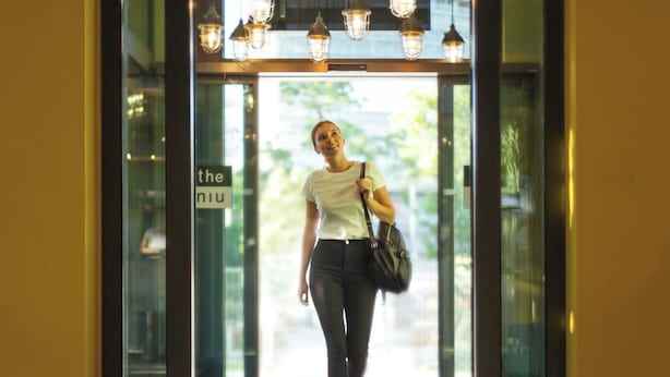 A person walking through a glass door entrance with a sign that reads 'the niu.' - Holiday Inn - the niu, Clink Hamburg Barmbek by IHG (Hamburg)
