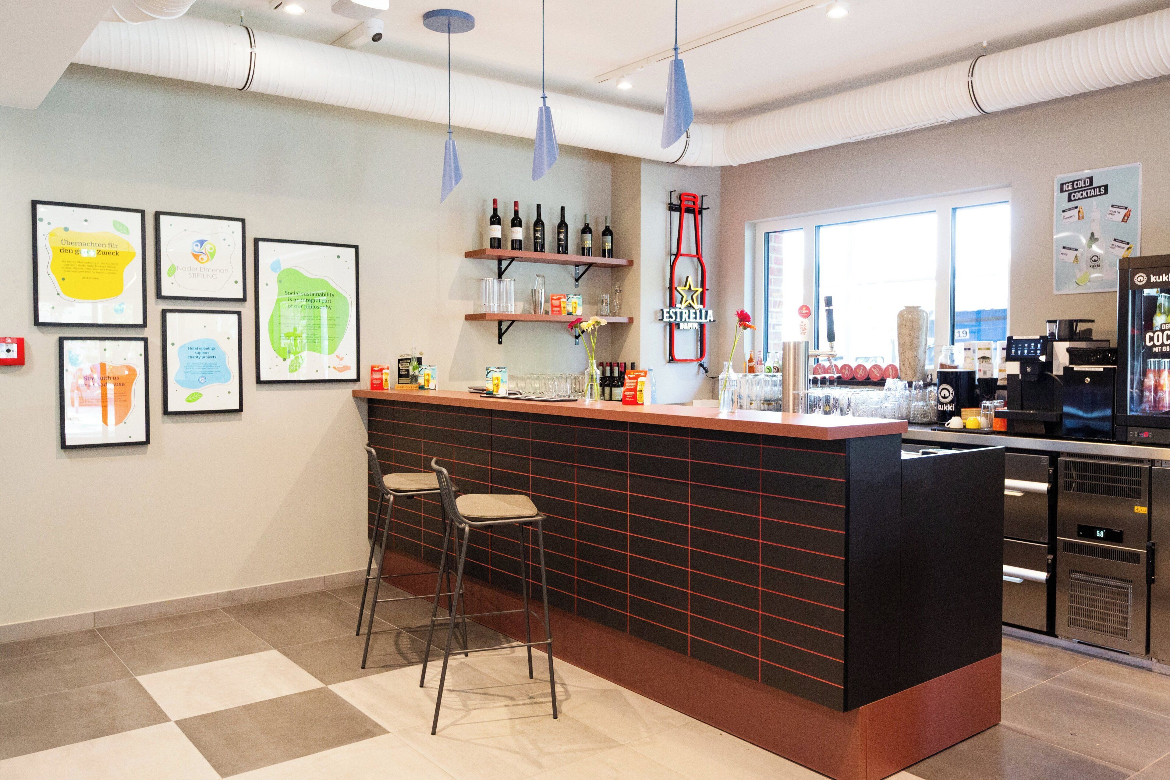 A bar area with stools, a counter, and framed artwork on the wall.