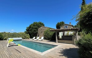 Une piscine avec des chaises longues et un bâtiment en pierre.