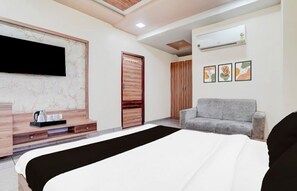 Una habitación de hotel moderna con una cama, un televisor montado en la pared, un sofá y un aire acondicionado.