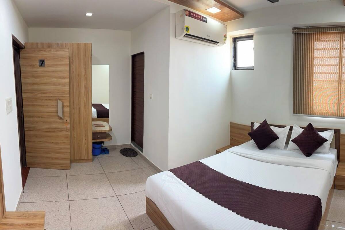 Habitación de hotel con cama, escritorio, armario y ventana con persianas.