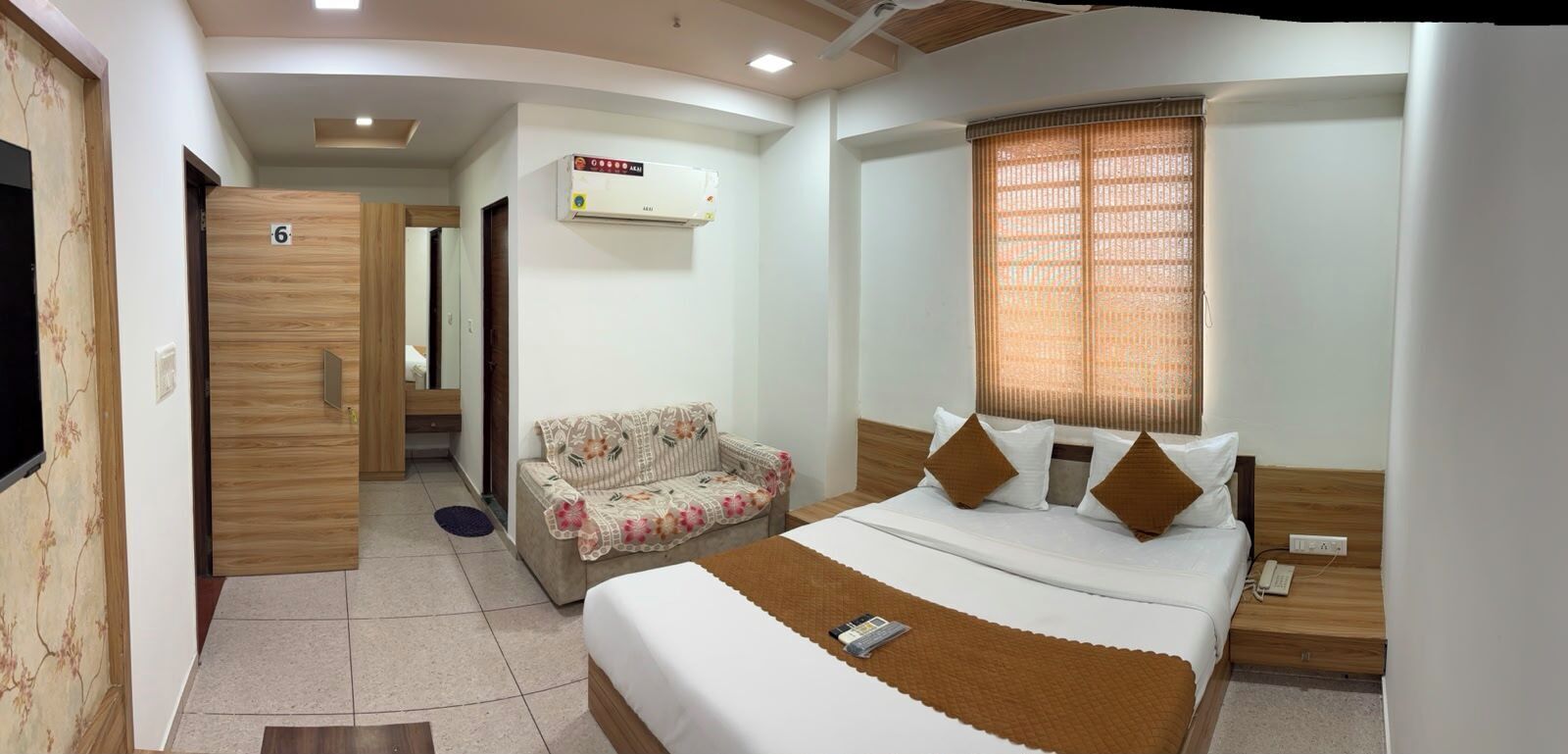 A bedroom with a bed, bedside table, nightstand, and a window with blinds.