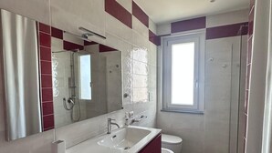 Moderni kylpyhuone, jossa on suuri peili, kaksi pesuallasta, wc ja suihku.