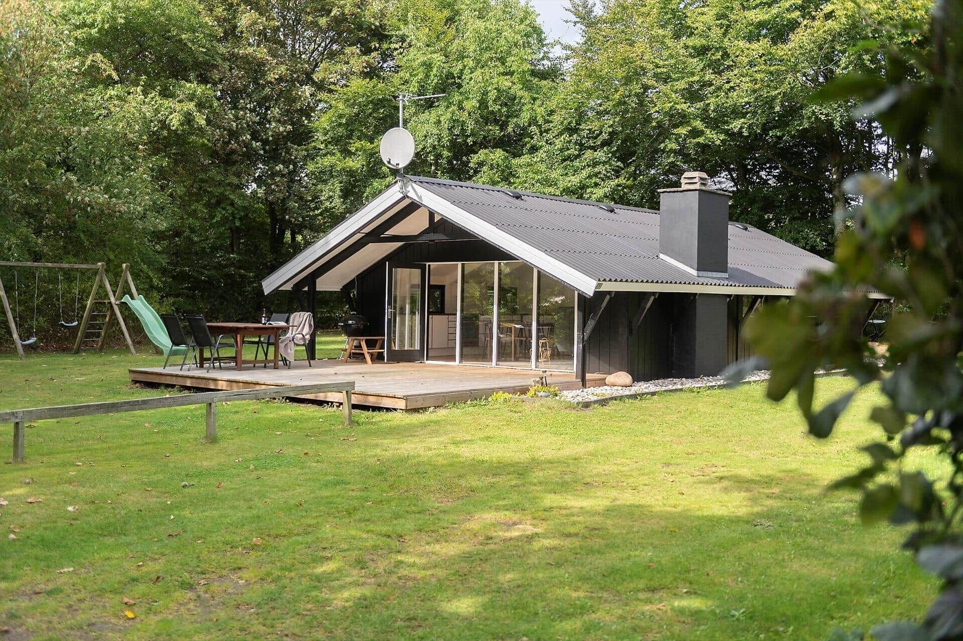 A modern house with a deck, a swing set, and a satellite dish.