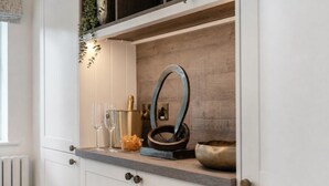 A kitchen counter with a metal bowl, two glasses, a gold container, and a decorative mirror. - NEW! Threadfold Townhouse - Peaceful Riverside Stay - Sleeps 6 (Bolton)