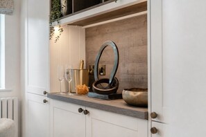 A kitchen counter with a metal bowl, two glasses, a gold container, and a decorative mirror.