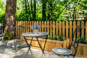 A round table with chairs, a wooden fence, and a tree in the background. - NEW! Threadfold Townhouse - Peaceful Riverside Stay - Sleeps 6 (Bolton)
