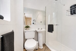 A modern bathroom with a toilet, sink, and shower.