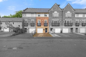 A row of residential buildings with multiple garages, a central entrance, and a small garden area.