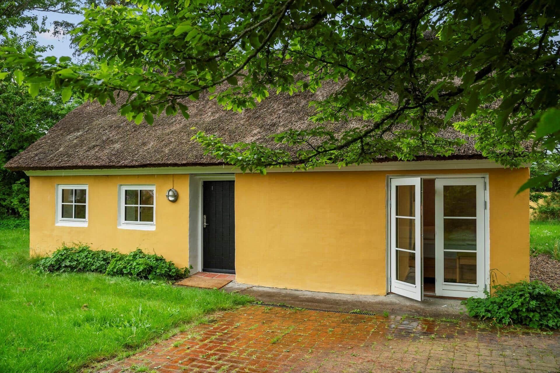 Een gelijkvloers huis met rieten dak, een voordeur en een klein portaal.
