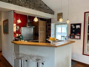 Eine Küche mit Kochinsel, Pendelleuchten, Stein Decke und einer Tafel mit Notizen.