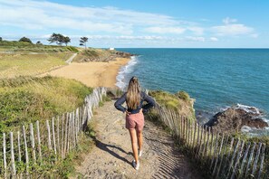 Ein Küstenpfad mit Holzzaun, der zu einem Strand führt.