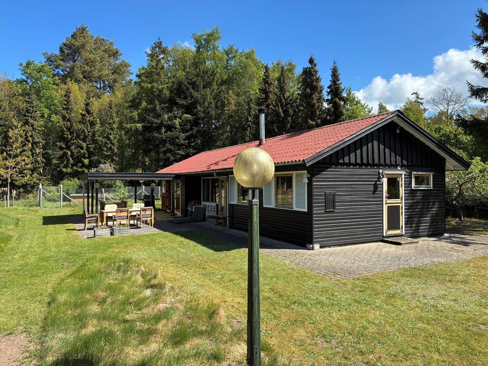 A cabin with a red roof, a porch with outdoor seating, and a large spherical light fixture.