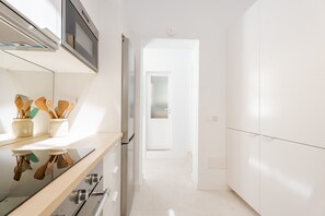 Eine moderne Küche mit Edelstahlgeräten, Holzkocherutensilien und einem weißen Innenraum.