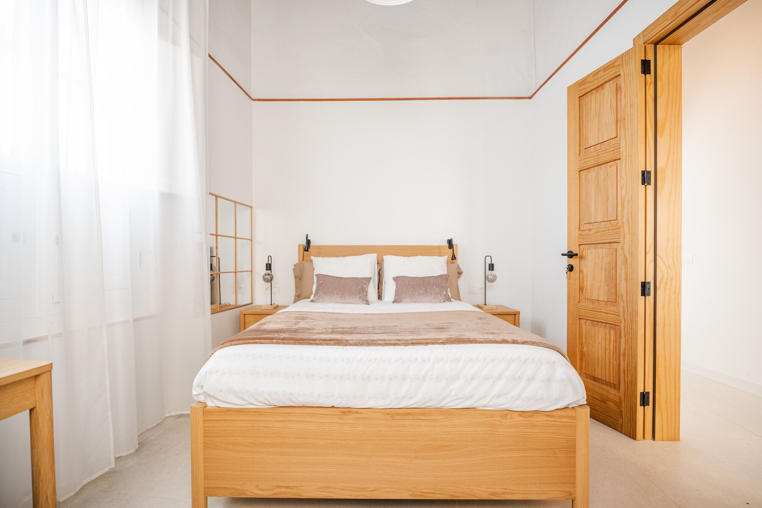 Una camera da letto con un letto in legno, comodini, uno specchio e un'armadio in legno.