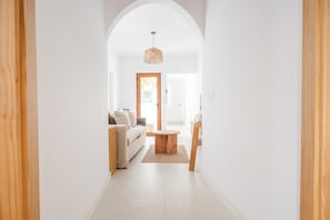 Ein Flur mit Holztür, einem runden Holztisch und einer Couch.