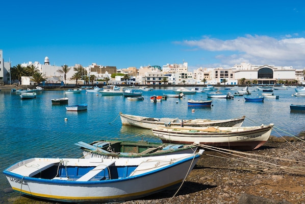 A harbor with boats, a building with a dome, and a clear sky. - Avocado Corner House • Charco de San Gines (Arrecife)