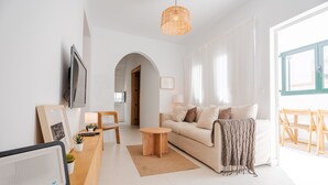 Ein modernes Wohnzimmer mit Sofa, Couchtisch, Fernseher und Blick ins Freie.